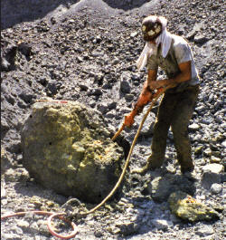 Working on an orpiment rich boulder using a drill hammer. CE photo.